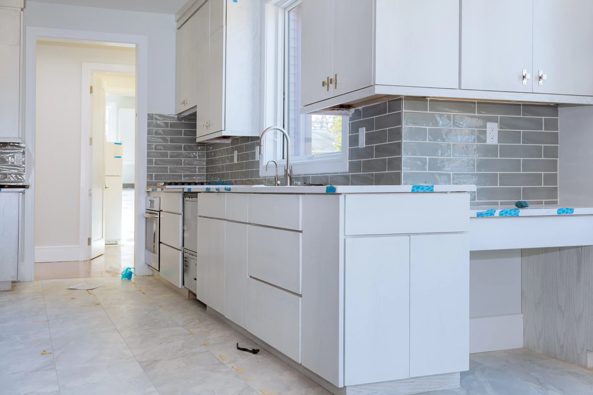 Köksrenovering i Solna – Nyrenoverat kök med vita skåp och grått kakel